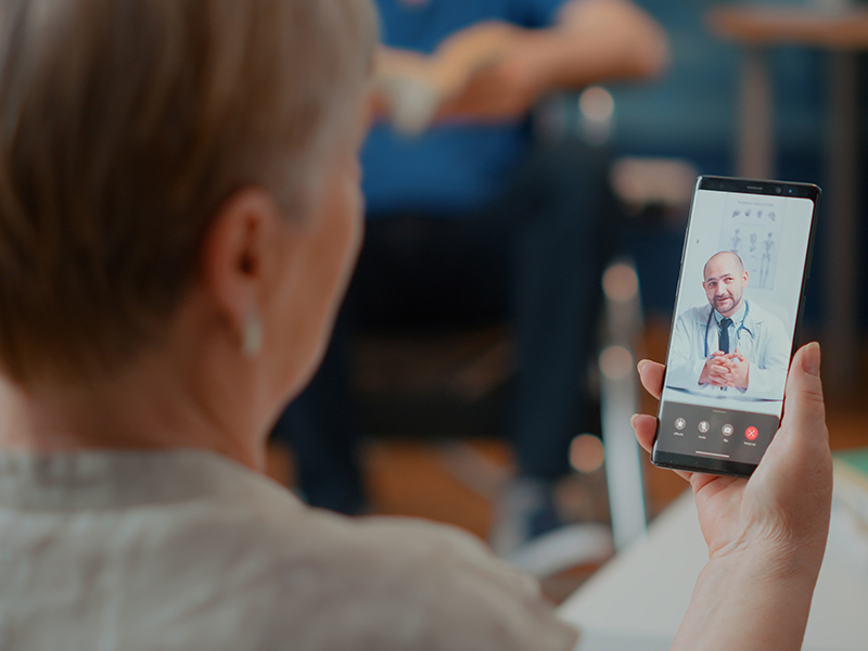 Woman uses smartphone to videoconference with doctor.