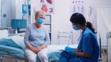 A nurse is taking with an older patient and writing down answers.